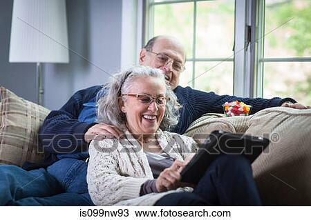 Senior couple using digital laptop on sofa at home View Large Photo Image Stock Image - Senior couple using digital laptop on sofa at home. Fotosearch