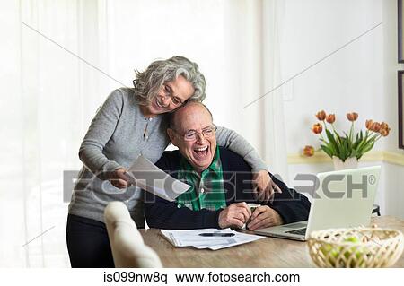 Senior couple using laptop at home, laughing View Large Photo Image Stock Photography - Senior couple using laptop at home, laughing. Fotosearch