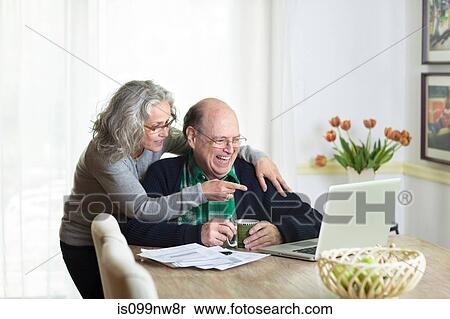 Senior couple using laptop at home, laughing View Large Photo Image Stock Photography - Senior couple using laptop at home, laughing. Fotosearch
