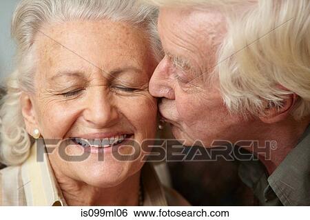 Stock Photograph - Senior man kissing senior woman on cheek. Fotosearch