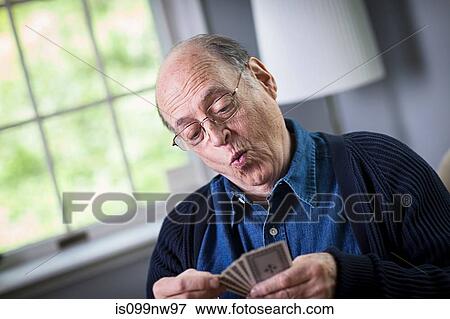 Stock Photo - Senior man playing card game at home. Fotosearch