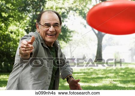 Stock Photograph - Senior man throwing red flying disc. Fotosearch