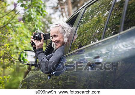 Stock Image - Senior woman photographing man car. Fotosearch