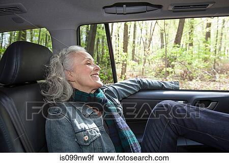 Stock Image - Senior woman relaxing in backseat of car. Fotosearch