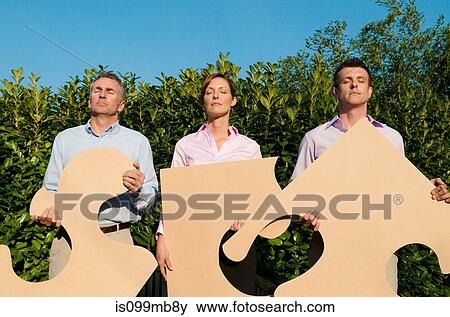 Three businesspeople holding shapes View Large Photo Image Stock Photo - Three businesspeople holding shapes. Fotosearch