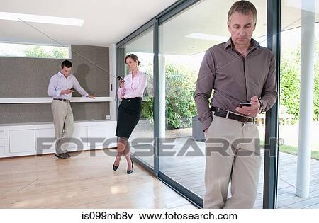 Stock Photo - Three businesspeople texting on cell phones in home office. Fotosearch