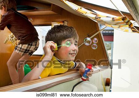 Two boys blowing bubbles out of caravan View Large Photo Image Stock Image - Two boys blowing bubbles out of caravan. Fotosearch