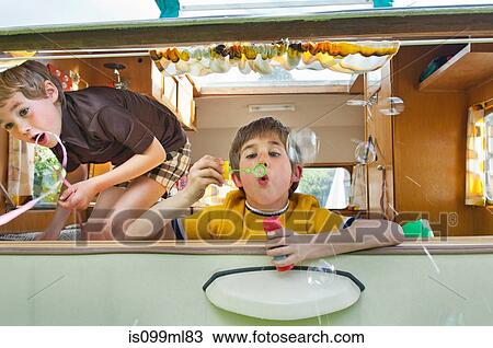 Two boys blowing bubbles out of caravan View Large Photo Image Stock Image - Two boys blowing bubbles out of caravan. Fotosearch