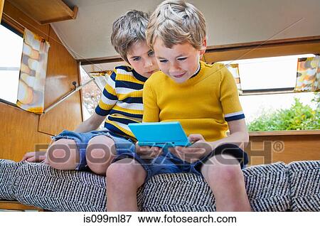 Two boys playing handheld video game View Large Photo Image Stock Photo - Two boys playing handheld video game. Fotosearch
