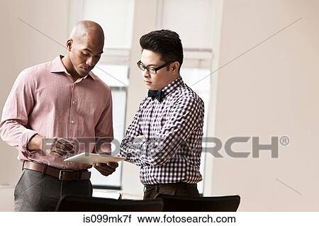 Two businessmen using digital tablet View Large Photo Image Stock Image - Two businessmen using digital tablet. Fotosearch