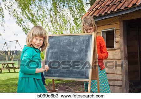 Two girls outdoors with blackboard View Large Photo Image Stock Image - Two girls outdoors with blackboard. Fotosearch