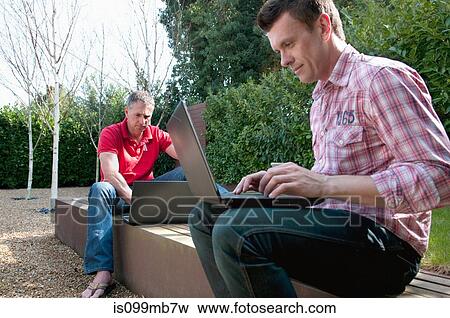 Two men using laptop in garden View Large Photo Image Stock Photo - Two men using laptop in garden. Fotosearch