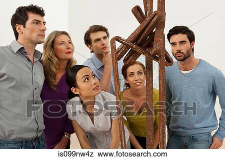 Stock Photo - Visitors looking at sculpture in art gallery. Fotosearch