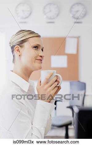 Woman drinking coffee in office View Large Photo Image Stock Photo - Woman drinking coffee in office. Fotosearch