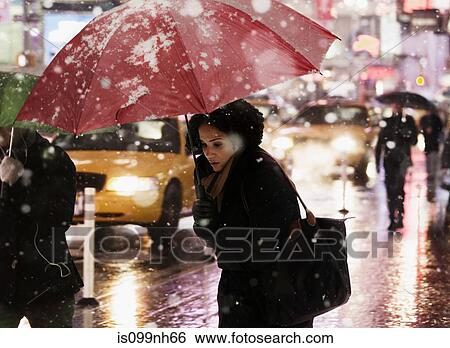 Woman walking through city street in snow shower View Large Photo Image Stock Photograph - Woman walking through city street in snow shower. Fotosearch