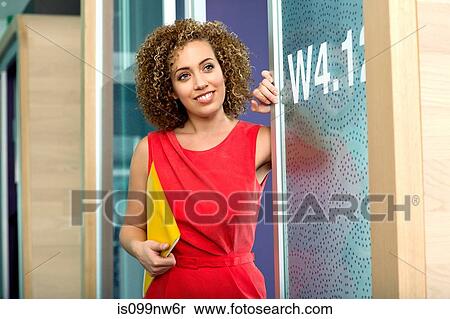 Young businesswoman holding file at doorway of office View Large Photo Image Stock Photography - Young businesswoman holding file at doorway of office. Fotosearch