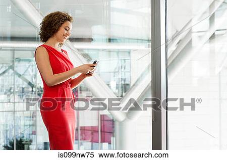 Young businesswoman in office using cellphone View Large Photo Image Stock Photography - Young businesswoman in office using cellphone. Fotosearch