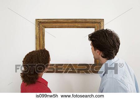 Young couple looking at blank image in picture frame View Large Photo Image Stock Image - Young couple looking at blank image in picture frame. Fotosearch