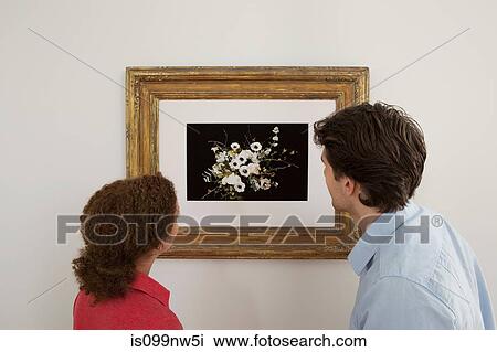 Stock Image - Young couple looking at print in picture frame. Fotosearch