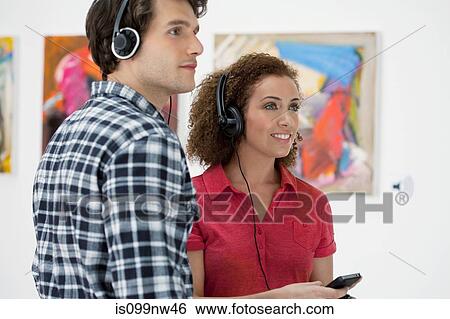 Young couple using audio guides in art gallery View Large Photo Image Stock Photograph - Young couple using audio guides in art gallery. Fotosearch
