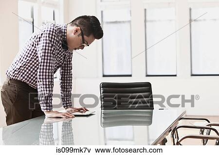 Stock Photo - Young man looking at digital tablet on desk. Fotosearch