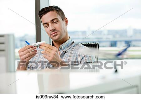 Young man looking at model aeroplane in office View Large Photo Image Picture - Young man looking at model aeroplane in office. Fotosearch