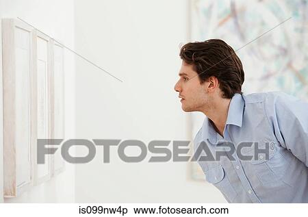 Young man looking at picture in art gallery View Large Photo Image Stock Photography - Young man looking at picture in art gallery. Fotosearch
