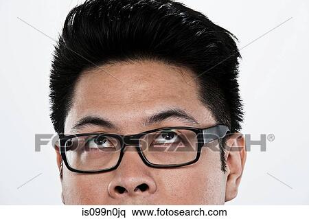 Stock Photography - Young man looking up against white background, close up. Fotosearch
