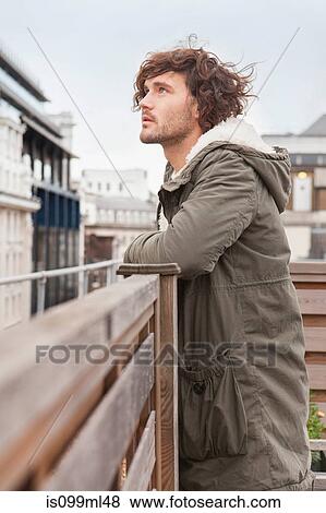 Young man on rooftop, looking up View Large Photo Image Stock Photo - Young man on rooftop, looking up. Fotosearch