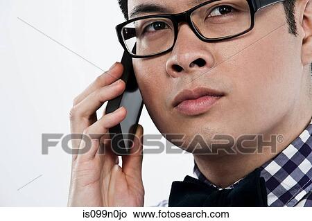 Picture - Young man using cellphone against white background. Fotosearch