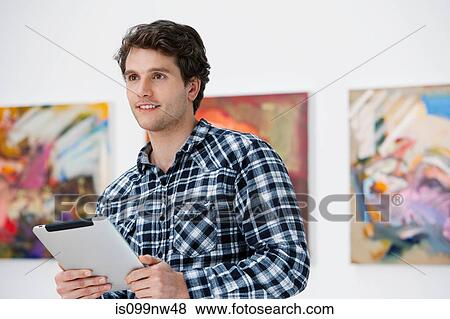 Young man using digital tablet in art gallery View Large Photo Image Stock Photo - Young man using digital tablet in art gallery. Fotosearch