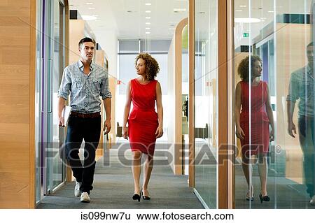 Young woman and man walking through office corridor View Large Photo Image Stock Photograph - Young woman and man walking through office corridor. Fotosearch
