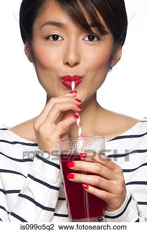 Young woman drinking from straw against white background View Large Photo Image Stock Image - Young woman drinking from straw against white background. Fotosearch