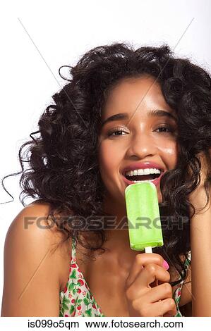 Picture - Young woman eating green popsicle, portrait. Fotosearch