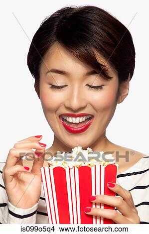 Young woman eating popcorn, studio shot View Large Photo Image Picture - Young woman eating popcorn, studio shot. Fotosearch