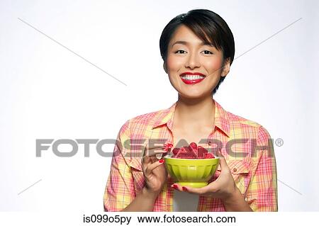 Young woman holding bowl of raspberries against white background View Large Photo Image Stock Photo - Young woman holding bowl of raspberries against white background. Fotosearch