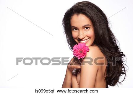 Stock Image - Young woman holding pink flower against white background. Fotosearch