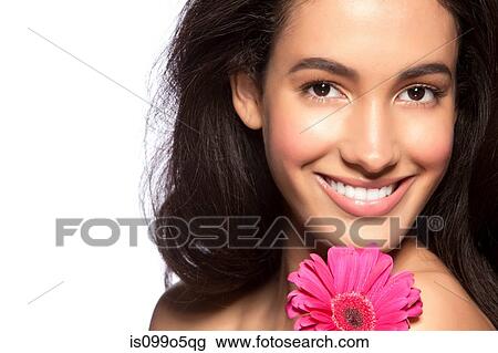Stock Image - Young woman holding pink flower against white background. Fotosearch
