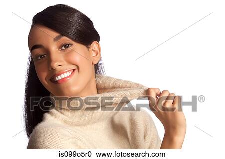 Stock Image - Young woman in polo neck smiling against white background. Fotosearch