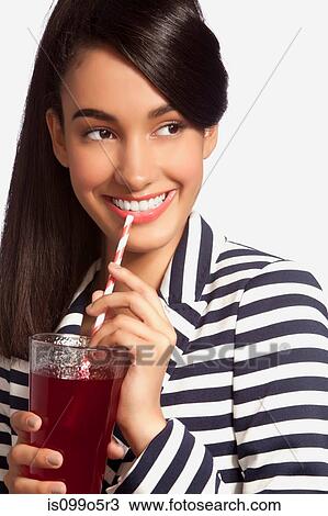 Stock Image - Young woman in striped top drinking from straw against white background. Fotosearch
