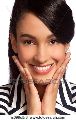 Stock Photograph - Young woman in striped top smiling against white background. Fotosearch