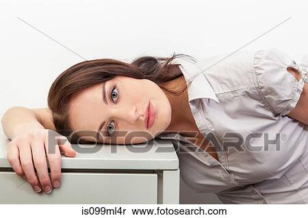 Stock Photography - Young woman leaning on filing cabinet, portrait. Fotosearch