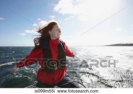 Stock Image - Young woman sailing with arms out. Fotosearch