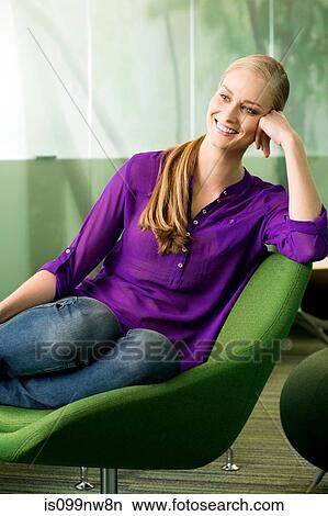 Picture - Young woman sitting in green chair in office. Fotosearch