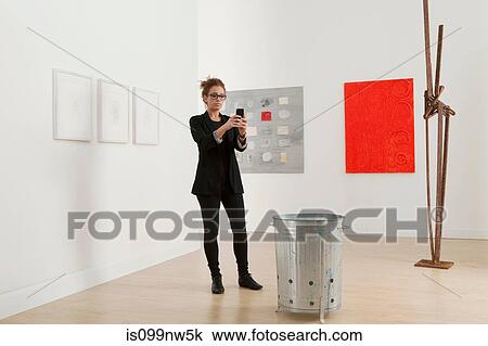 Young woman using cellphone to take picture of artwork in gallery View Large Photo Image Stock Image - Young woman using cellphone to take picture of artwork in gallery. Fotosearch