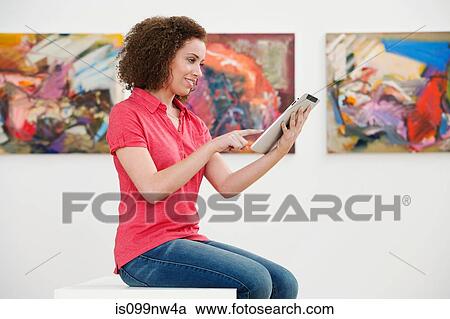 Young woman using digital tablet in art gallery View Large Photo Image Stock Image - Young woman using digital tablet in art gallery. Fotosearch