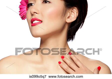 Stock Photo - Young woman wearing pink flower in hair against white background. Fotosearch
