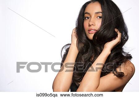 Stock Image - Young woman with hands in hair against white background. Fotosearch