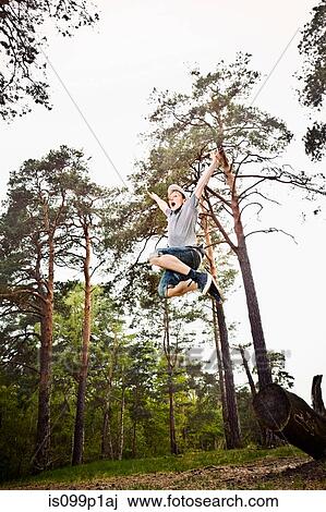 Stock Image - Boy jumping in forest. Fotosearch