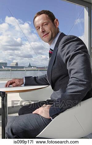 Stock Image - Businessman sitting in airport, portrait. Fotosearch